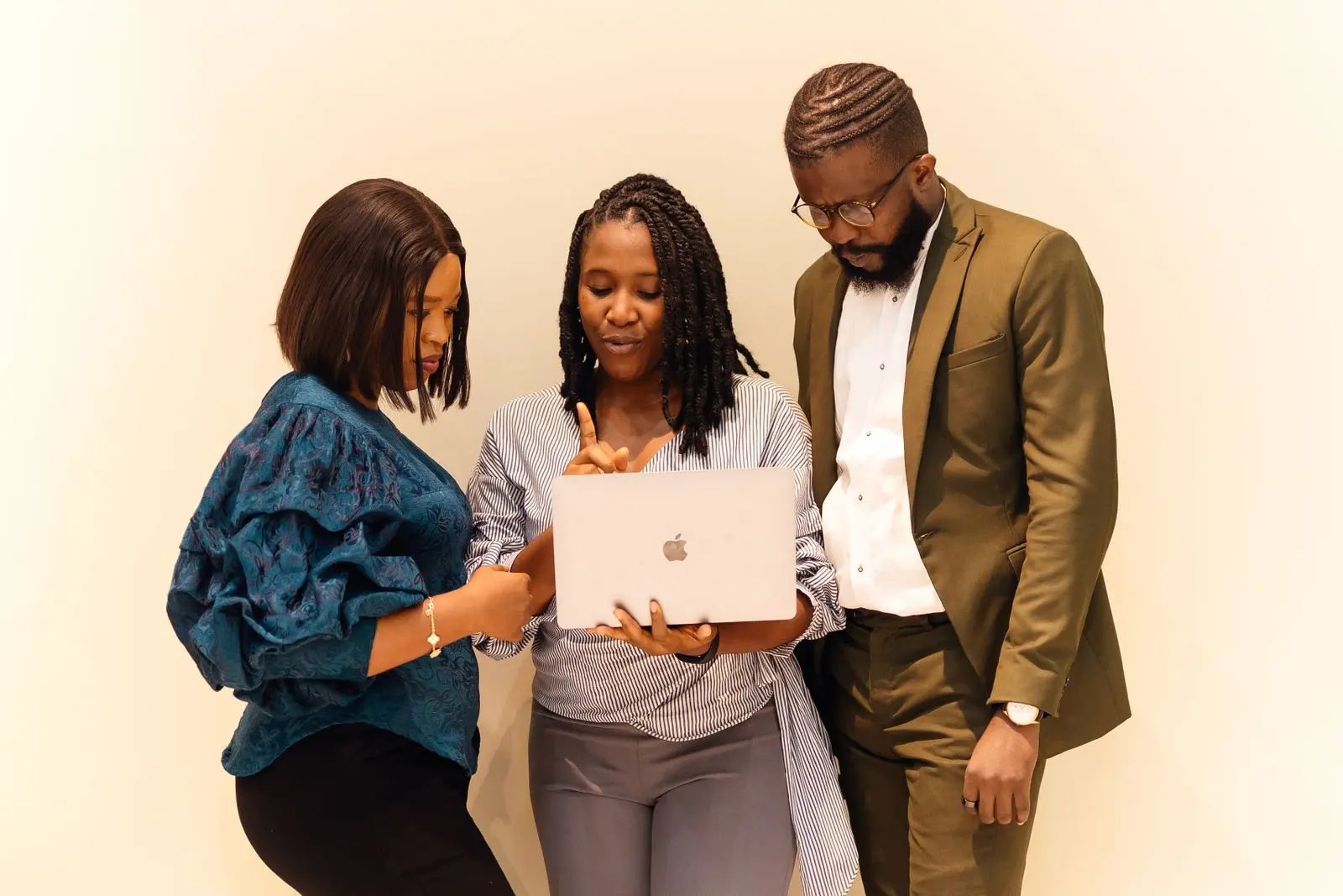 Three colleagues reviewing work on a laptop in a Lagos office
